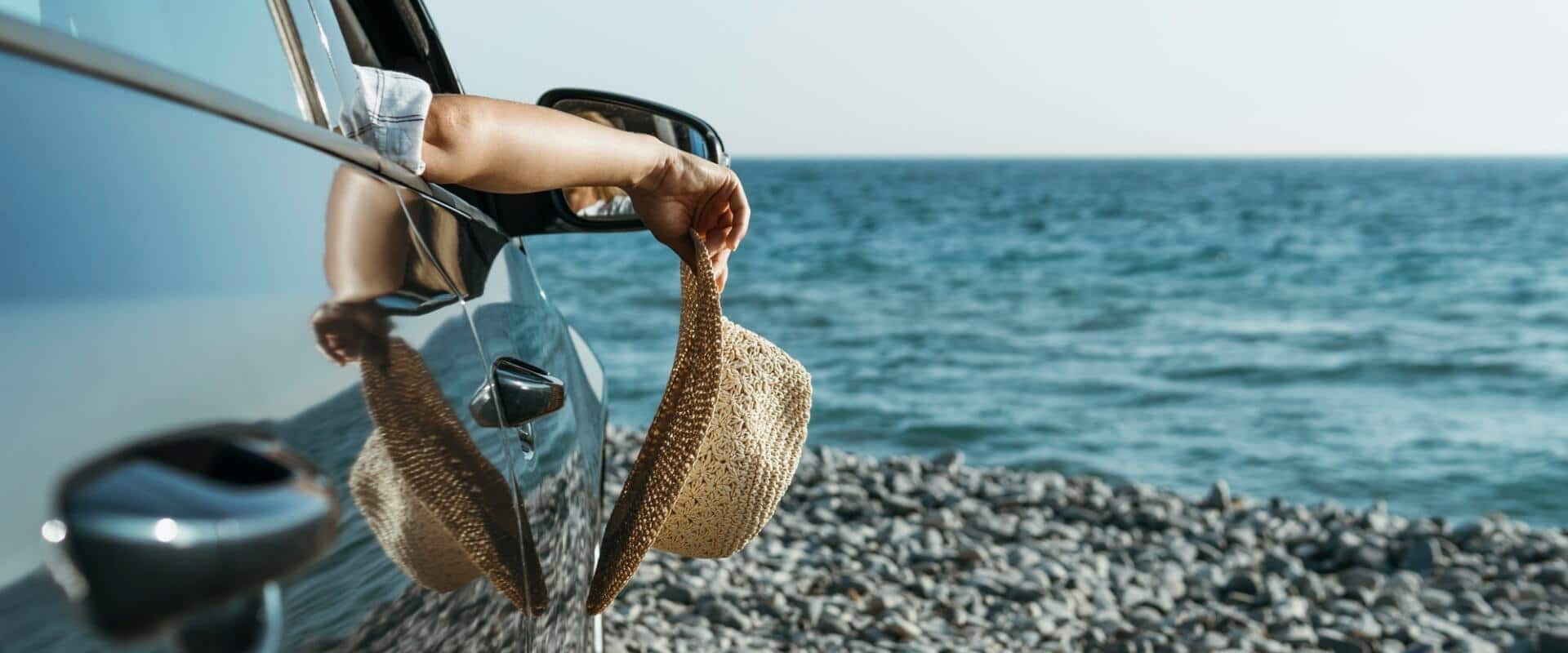 Mid Shot Woman Hand Hanging Out Car Window Holding Hat Near Sea